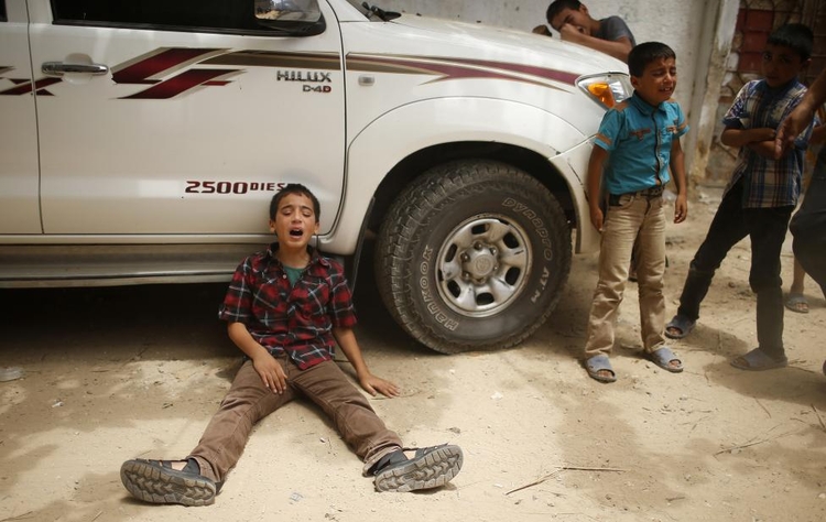 fot. Mohammed Salem / Reuters / 13 lipca 2014  Gaza, Palestyna  Pogrążony w żałobie (po lewej) syn jednego z członków rodziny Tajsira Al-Batsha, który - według oficjalnych oświadczeń pobliskiego szpitala - zginął wskutek izraelskiego nalotu powietrznego.